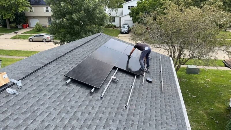 A Person Installs Solar Panels on A Residential Rooftop, Enhancing the Home's Sustainable Energy Capabilities