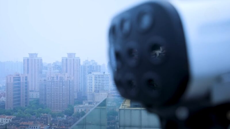 Close-Up of A Mantis Computer Overlooking a Dense, Urban Landscape with High-Rise Buildings Shrouded in Haze