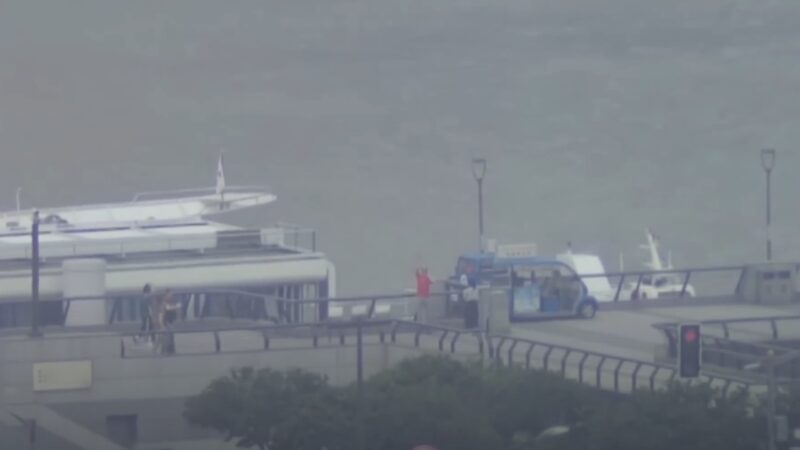 Hazy View of A Waterfront with A Boat and People, Demonstrating a Scene Where Mantis Computer Technology Could Be Utilized in Search and Rescue Missions