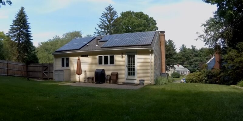 Suburban Home with Solar Panels Installed on The Roof, Surrounded by A Lush Green Yard