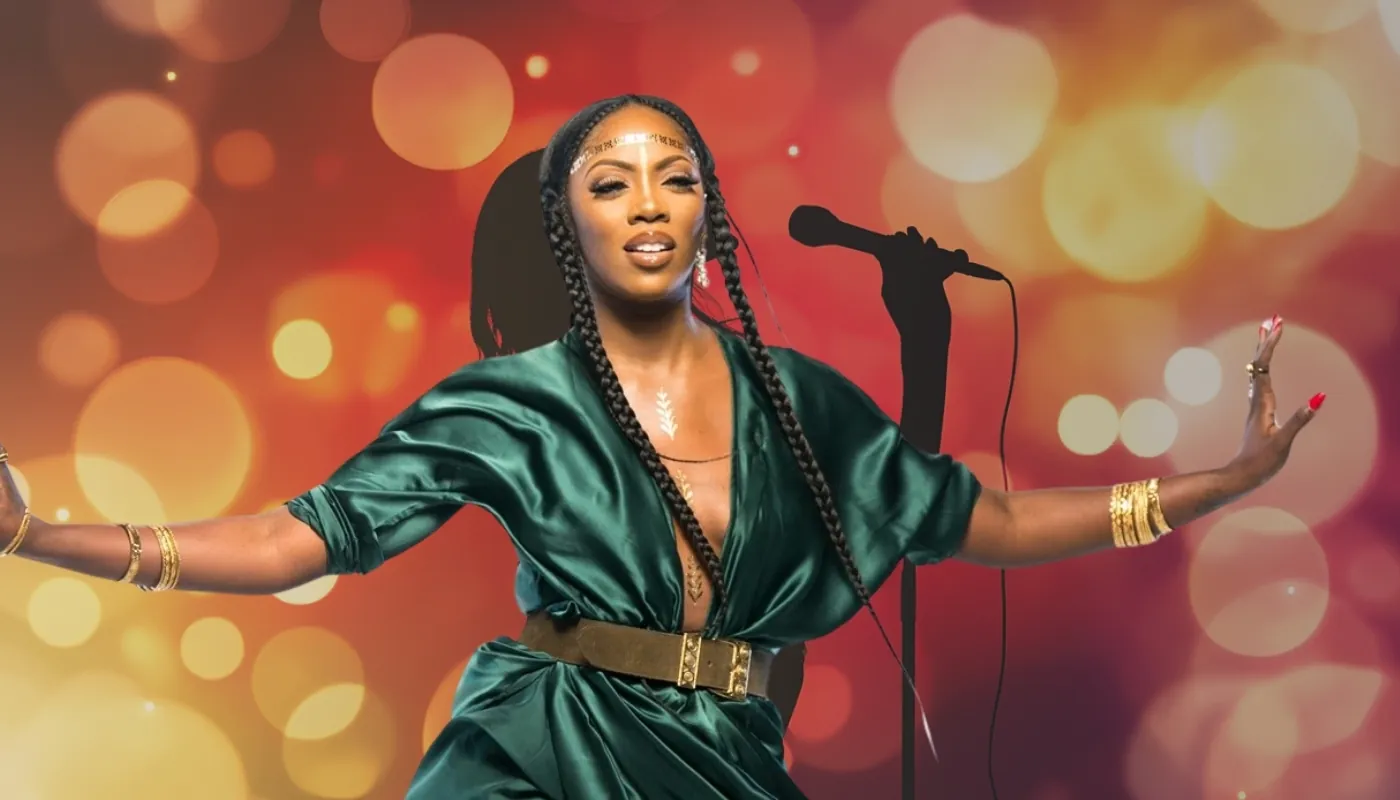A vibrant singer in a green outfit performing against a glowing background