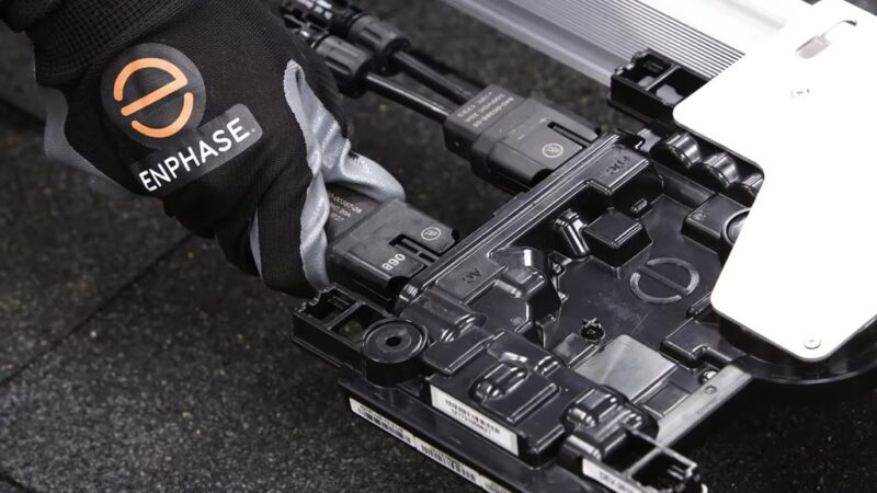 Technician wearing Enphase gloves handling a microinverter during solar panel setup