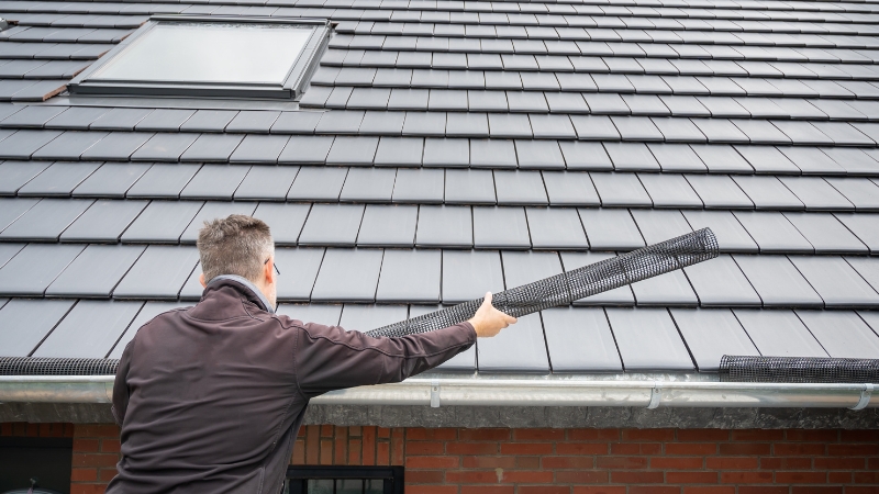 Man placing a gutter guard on a roof