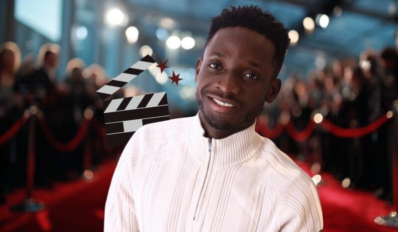 Actor Chimezie Imo in a white sweater smiling on the red carpet