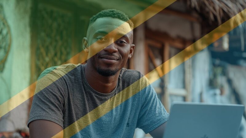 Young Tanzanian freelancer working on laptop near café in Dar es Salaam