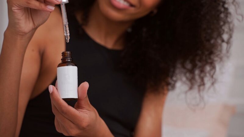 Woman holding a dropper bottle of cannabis oil, preparing to use it