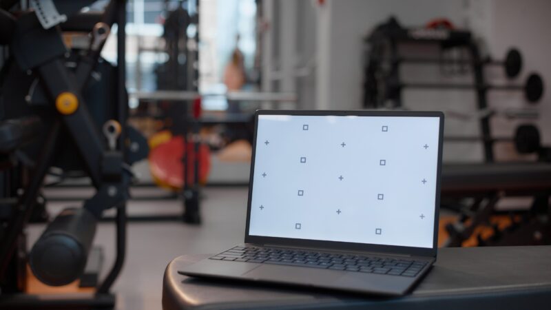 Laptop displays workout screen content inside a gym