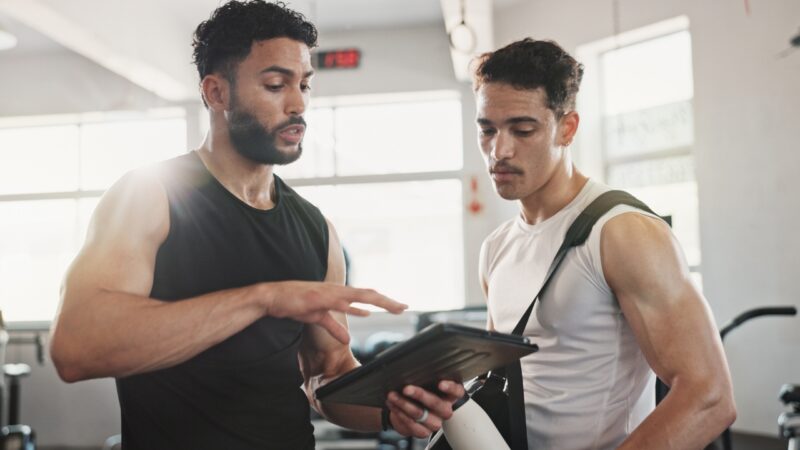 Trainer shows a gym member class details on a tablet