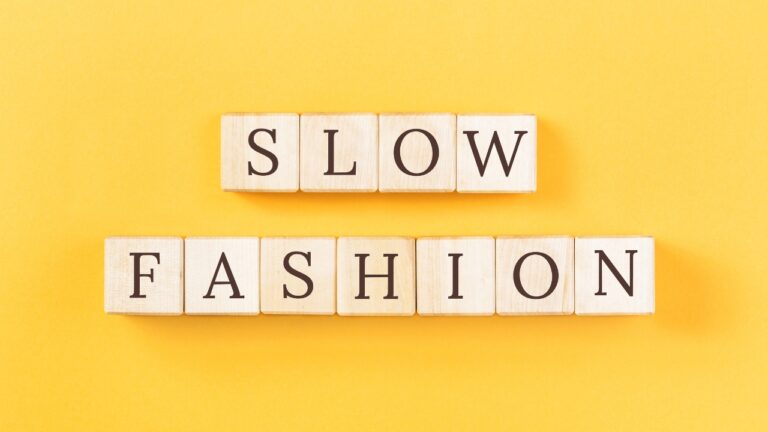 Wooden letter tiles spell slow fashion on a bright yellow background